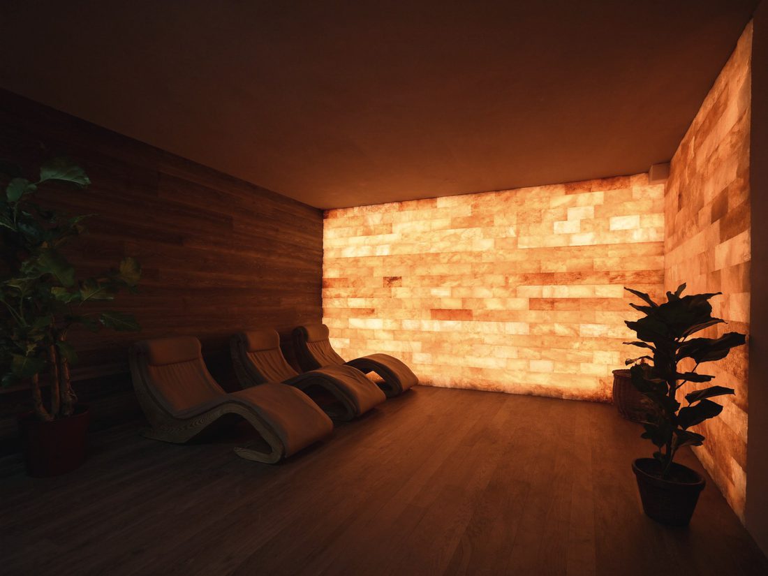 The salt room: zero-gravity chairs before a glowing amber salt wall.