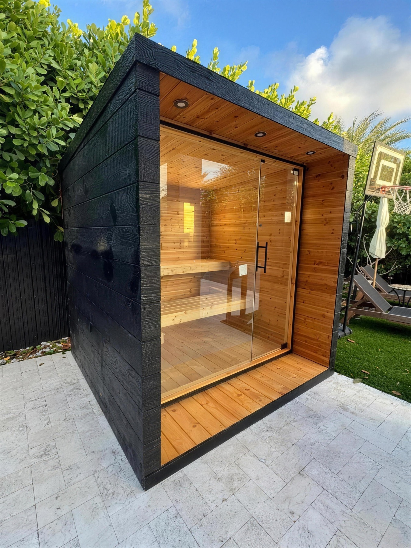 Charred-cedar sauna on a travertine patio