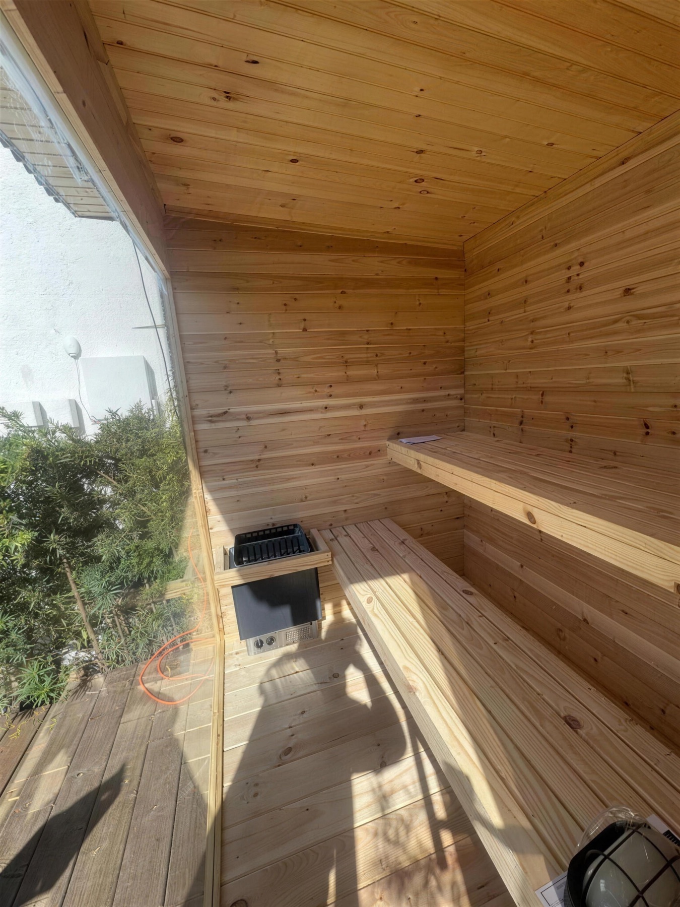 Sauna interior: benches, heater and window in hard sunlight